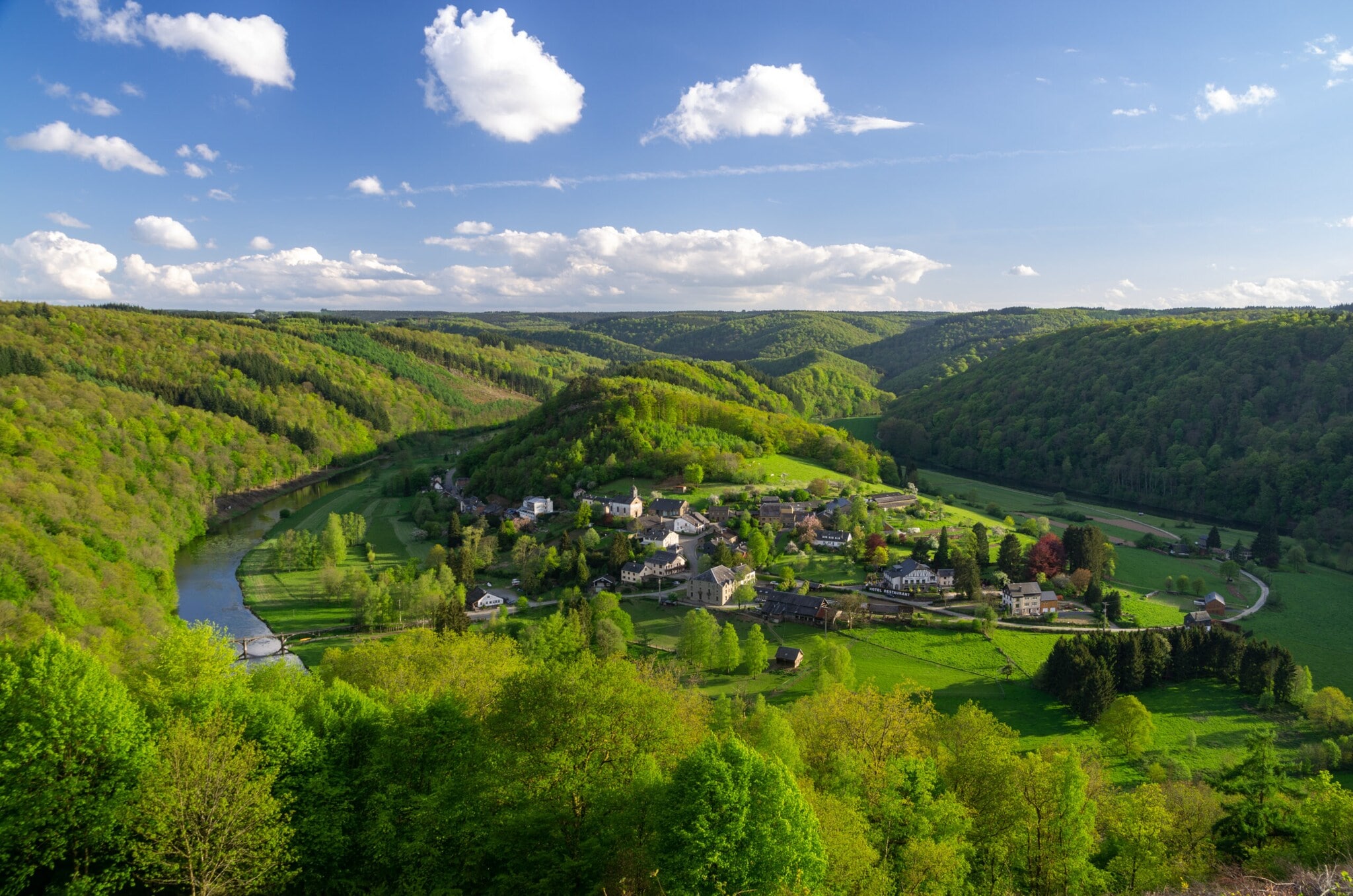 Kleine Ortschaft in einem Flusstal, weitläufig umgeben von hügeliger Waldlandschaft Kleine Ortschaft in einem Flusstal, weitläufig umgeben von hügeliger Waldlandschaft