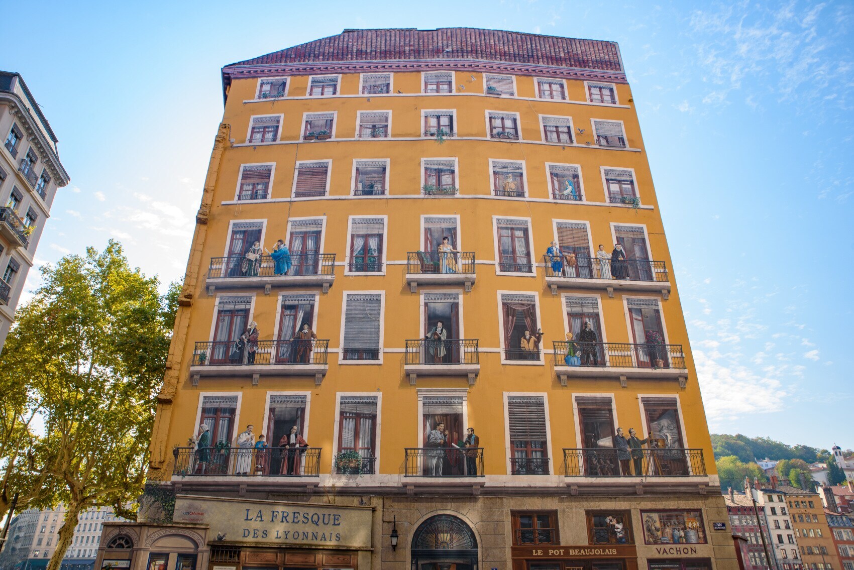 Ein Fresko an einer Hauswand, das unterschiedliche Personen auf Balkonen darstellt Ein Fresko an einer Hauswand, das unterschiedliche Personen auf Balkonen darstellt