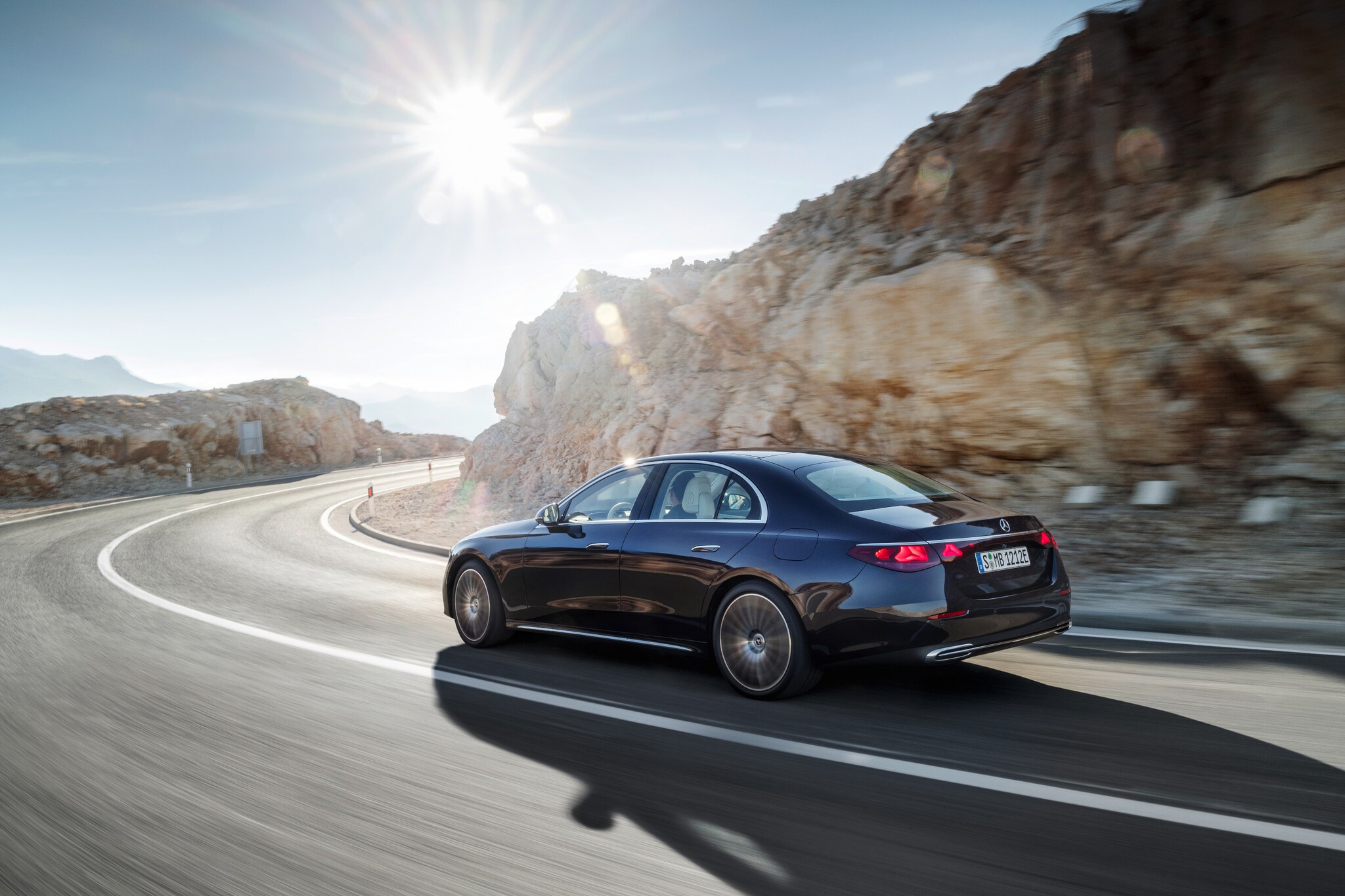 Ein schwarzer Mercedes seitlich von hinten in einer Kurve auf einer Bergstraße