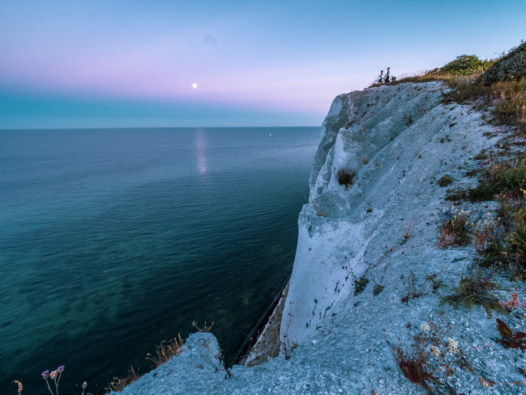 Zwei Radfahrende stehen an den Klippen von Møns Klint und schauen aufs Meer Zwei Radfahrende stehen an den Klippen von Møns Klint und schauen aufs Meer