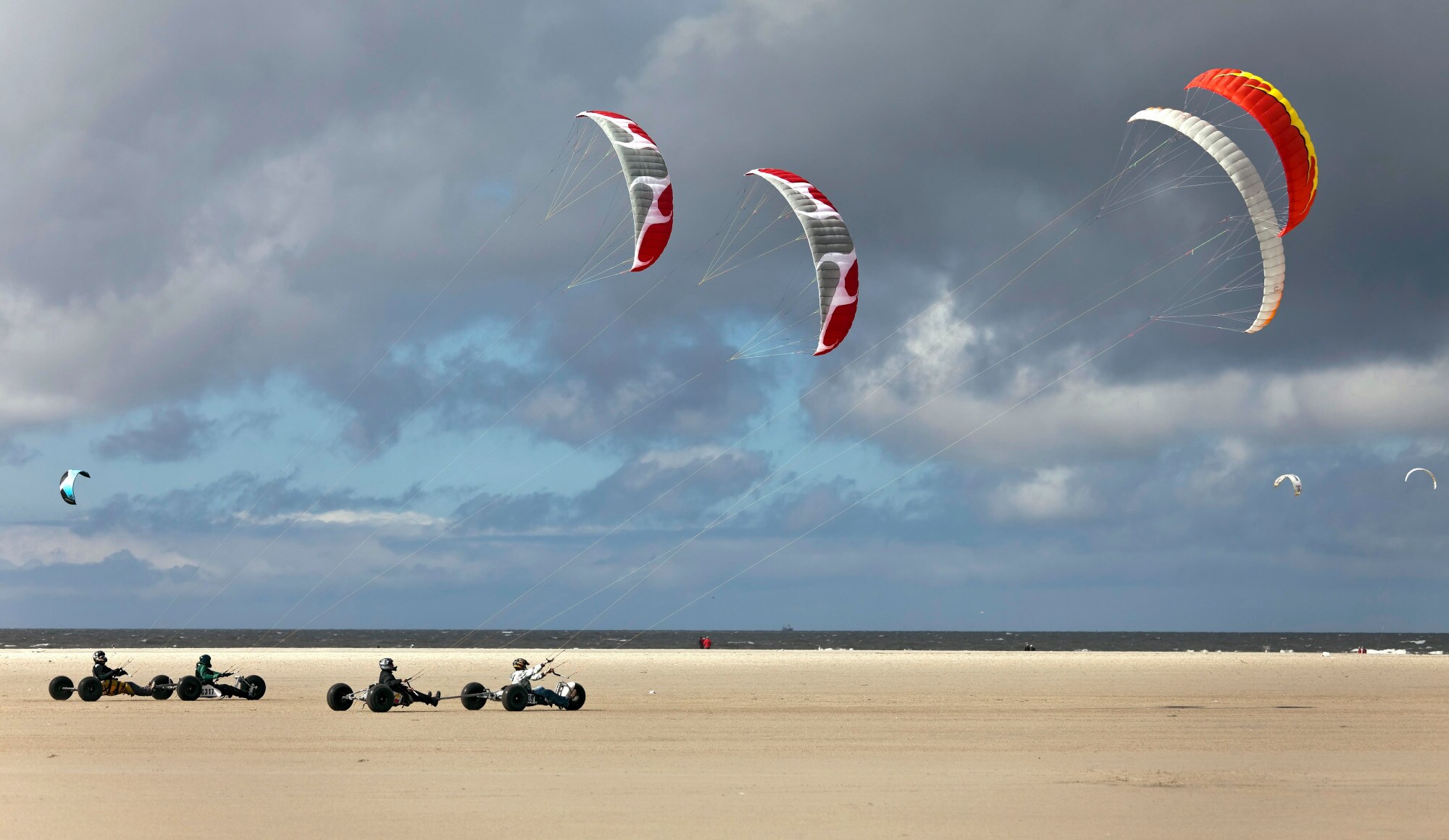 Kitebuggys am Strand von St. Peter Ording vor bewölktem Himmel Kitebuggys am Strand von St. Peter Ording vor bewölktem Himmel
