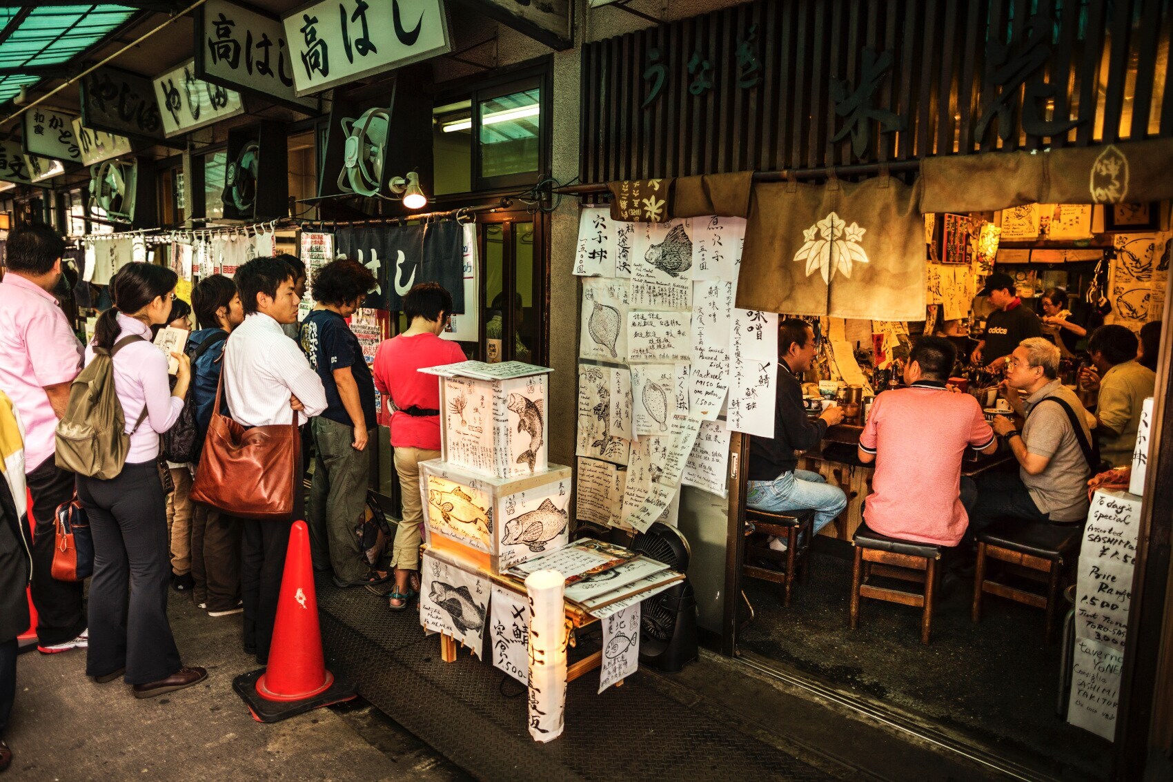 Mehrere Personen stehen in einer Gasse vor Straßenrestaurants an