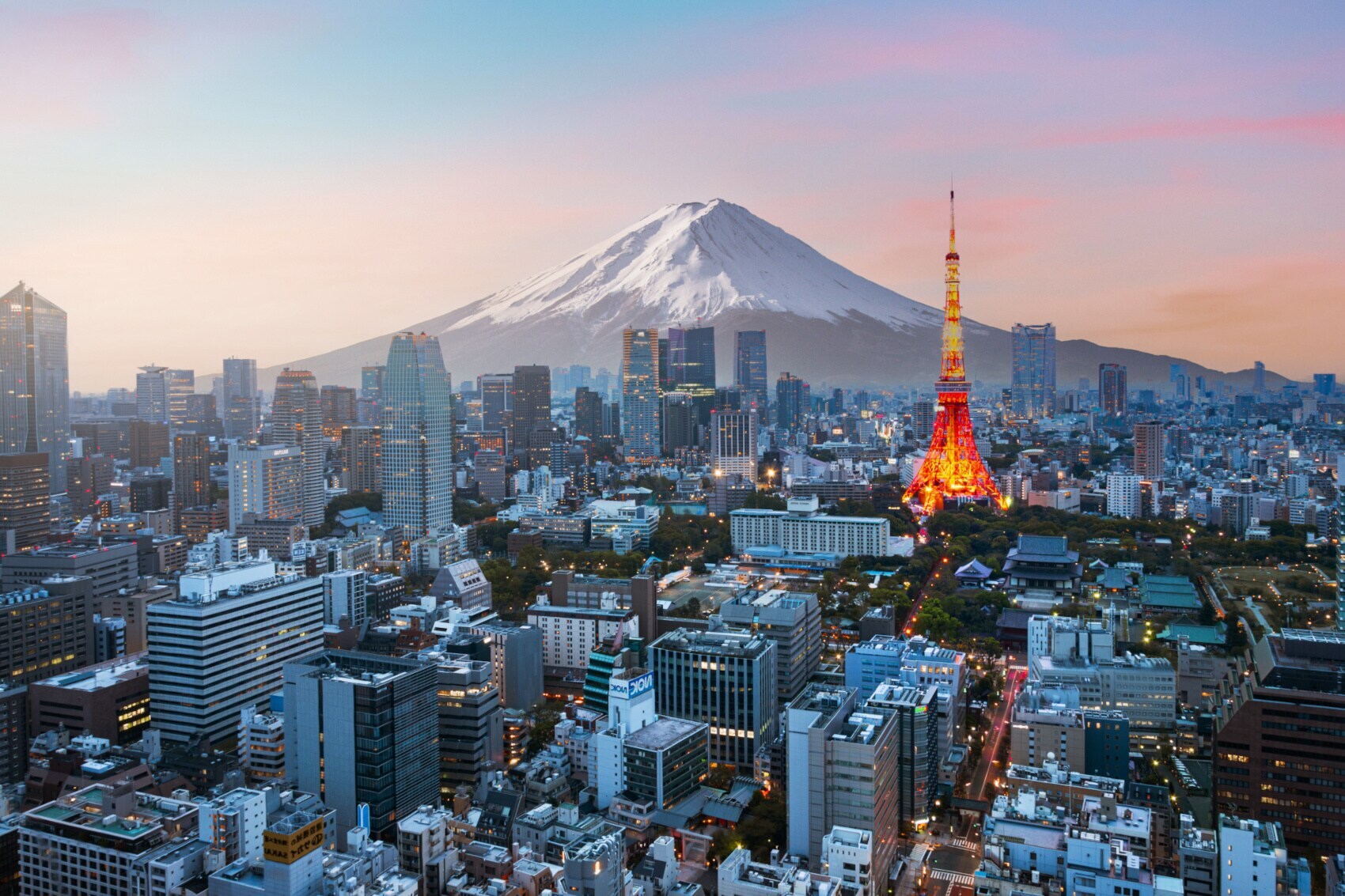 Skyline von Tokio mit beleuchtetem Fernsehturm vor schneebedecktem Fuji in der Abenddämmerung