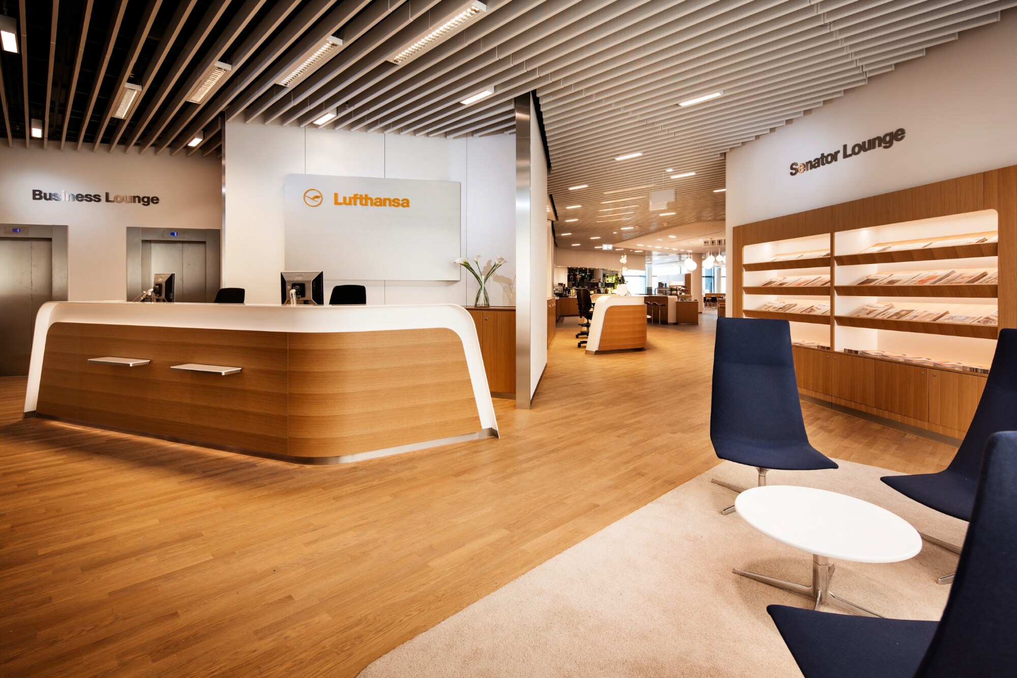 Empfangsbereich einer Lufthansa-Flughafen-Lounge mit Infodesk und Sitzgelegenheiten