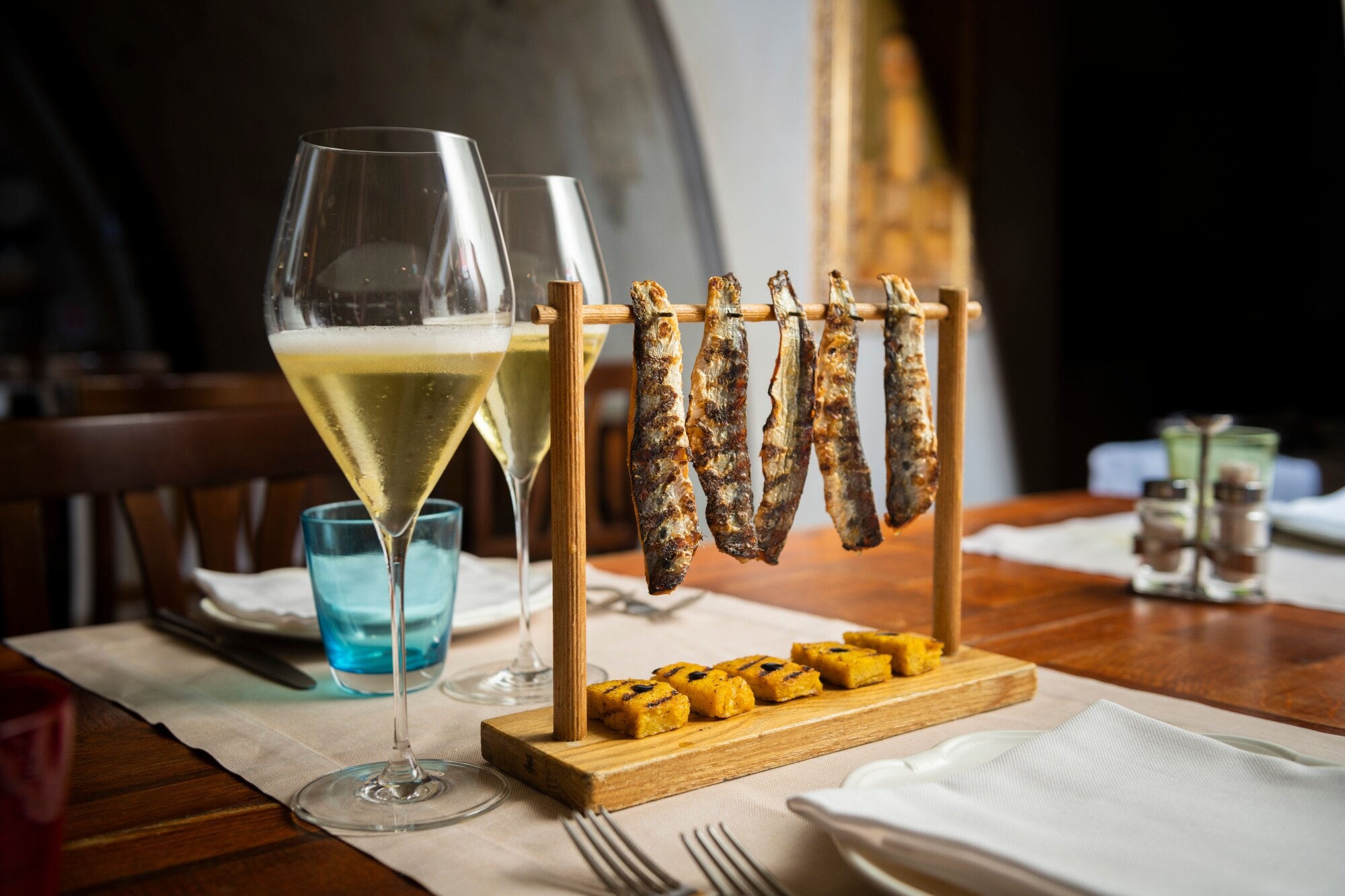 Zwei Gläser mit perlendem Schaumwein auf einem gedeckten Tisch mit Snacks Zwei Gläser mit perlendem Schaumwein auf einem gedeckten Tisch mit Snacks
