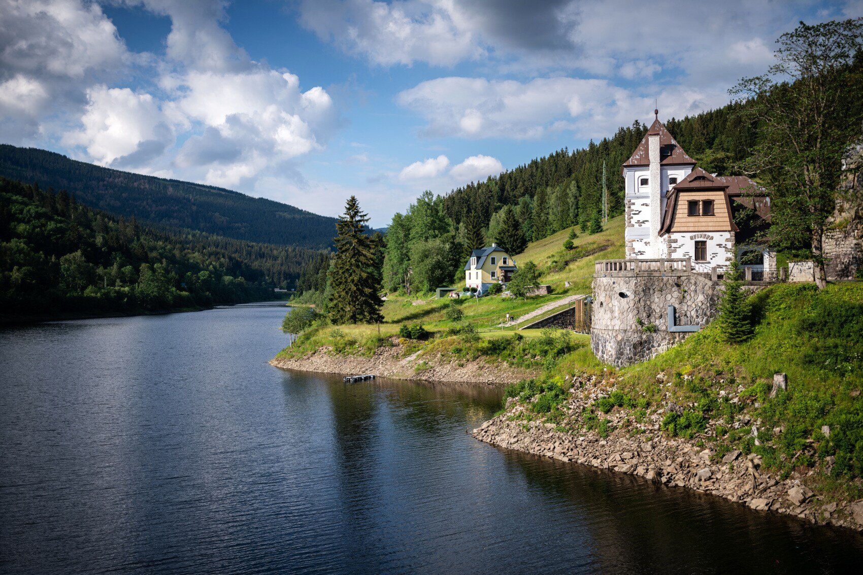 Ein See in einer hügeligen Landschaft, am Ufer steht eine Dorfkirche