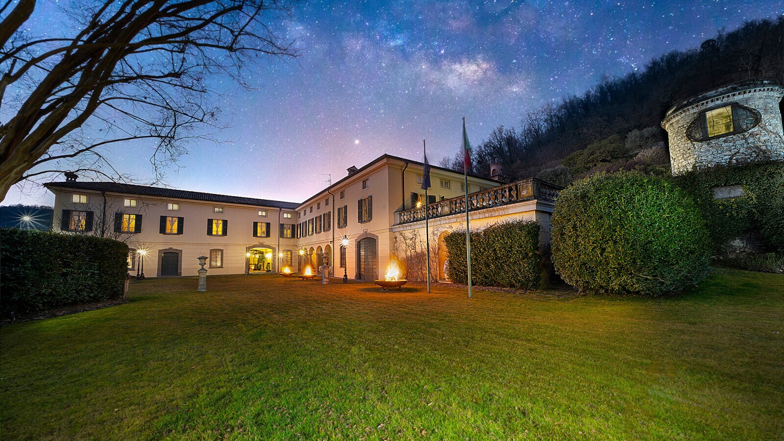 Beleuchtetes, herrschaftliches Gebäude eines Weingutes mit Gartenanlage am Abend