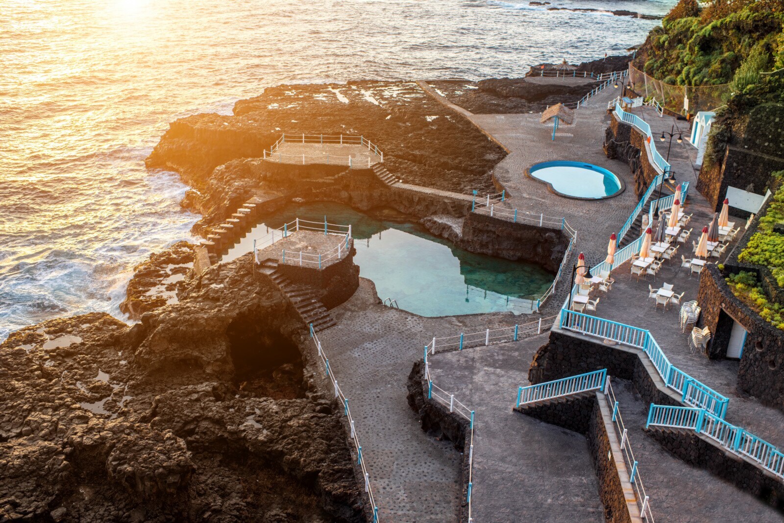 Aufsicht eines natürlichen Meerwasserpools an einer Felsküste vor der Terrasse einer Hotelanlage