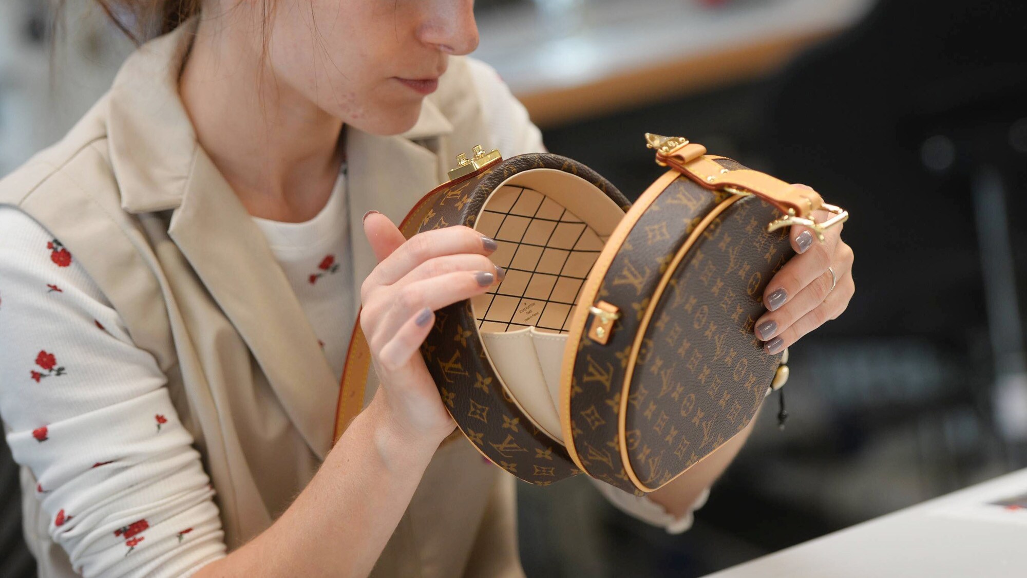 Eine Frau kontrolliert eine braune, runde Lederhandtasche mit Tumbler-Schloss von Louis Vuitton