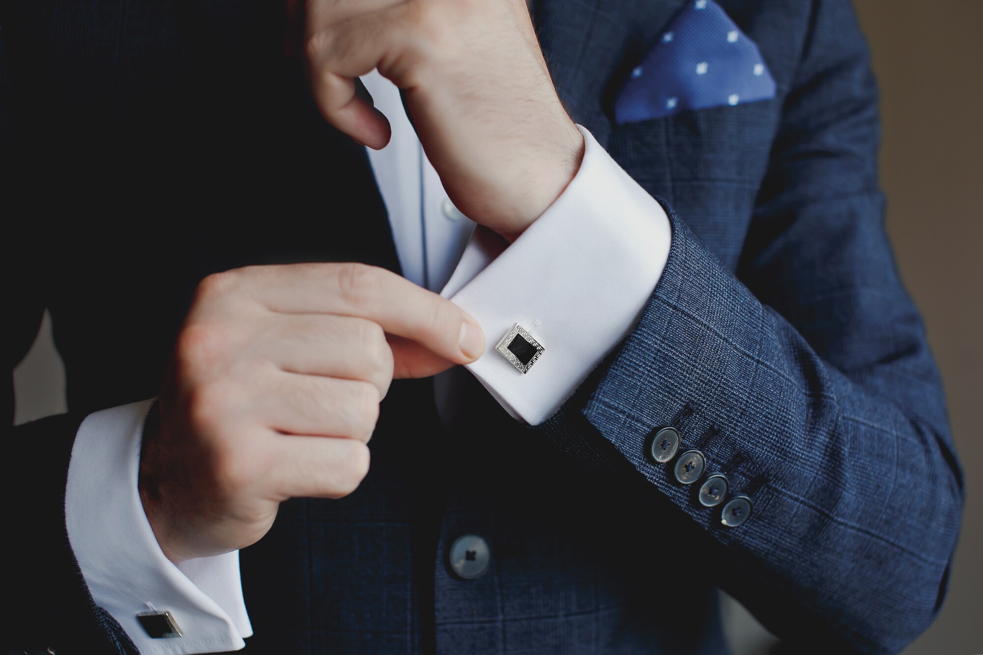 Oberkörper eines Mannes im blauen Anzug mit eleganten Manschettenknöpfen an weißen Hemdmanschetten. Oberkörper eines Mannes im blauen Anzug mit eleganten Manschettenknöpfen an weißen Hemdmanschetten.