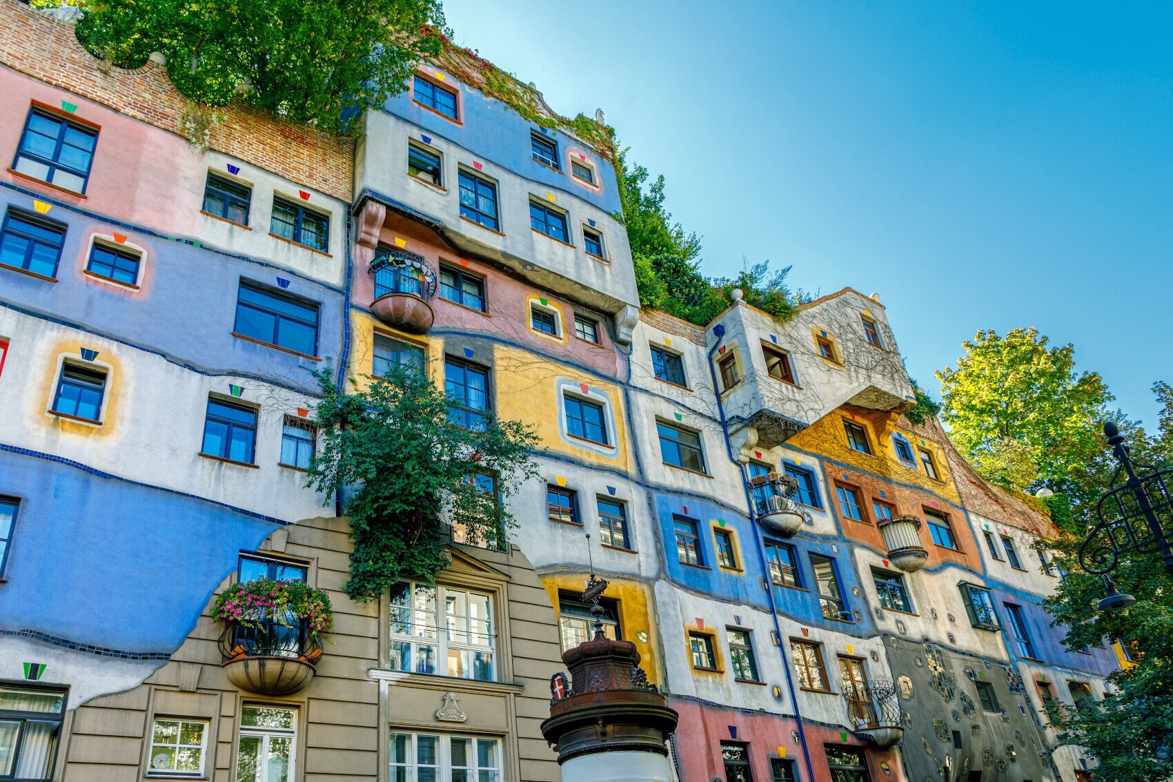 Außenansicht eines Hundertwasserhauses mit bunter und begrünter Fassade Außenansicht eines Hundertwasserhauses mit bunter und begrünter Fassade