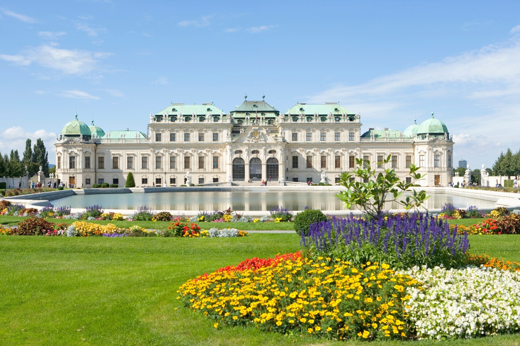 Barockschloss Belvedere mit Teich und Parkanlage mit blühenden Pflanzen im Vordergrund Barockschloss Belvedere mit Teich und Parkanlage mit blühenden Pflanzen im Vordergrund