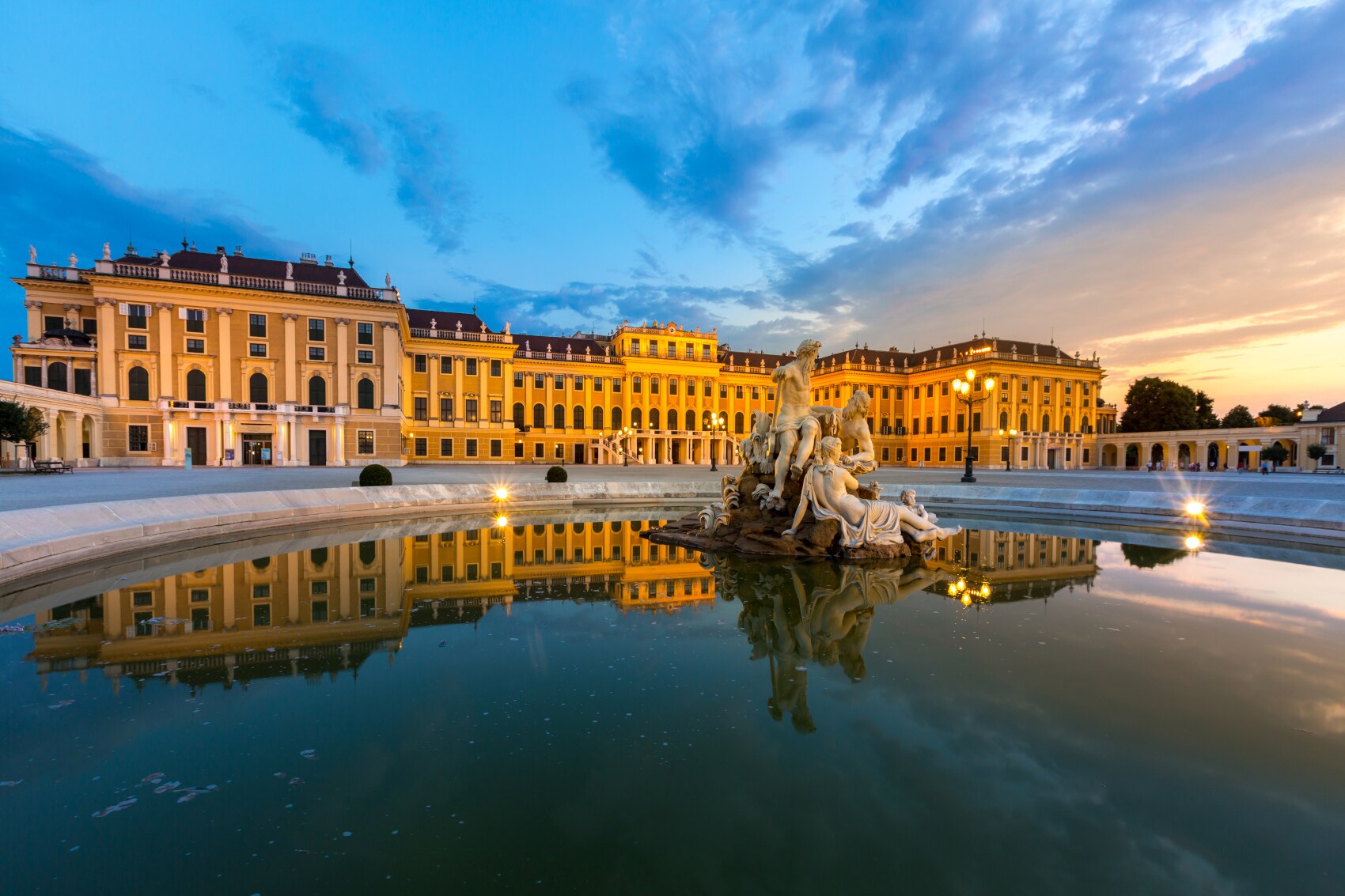 Beleuchtetes Schloss Schönbrunn mit Brunnen im Vordergrund bei Nacht Beleuchtetes Schloss Schönbrunn mit Brunnen im Vordergrund bei Nacht