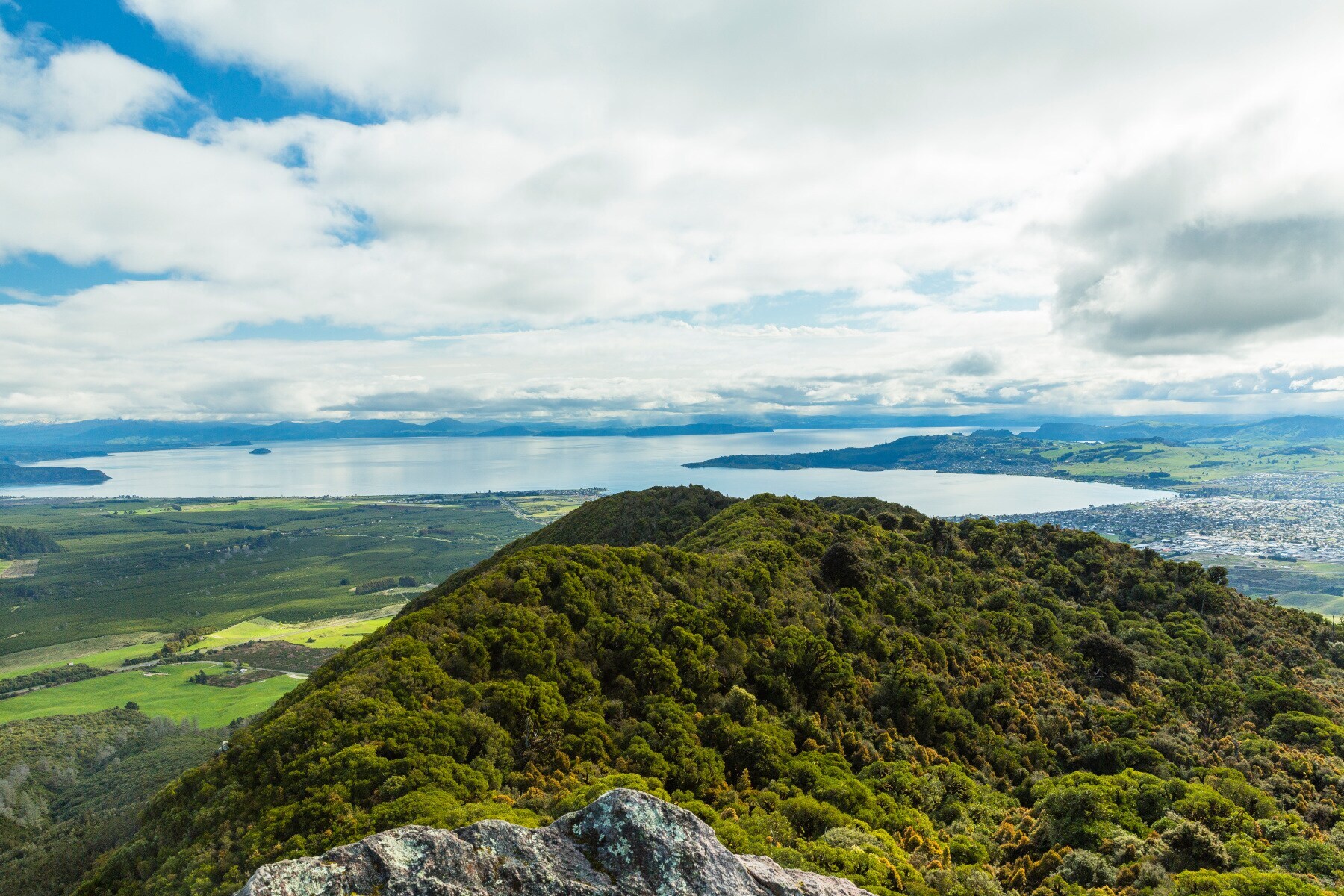 Blick über einen bewaldeten Bergkamm hin zu einem großen See