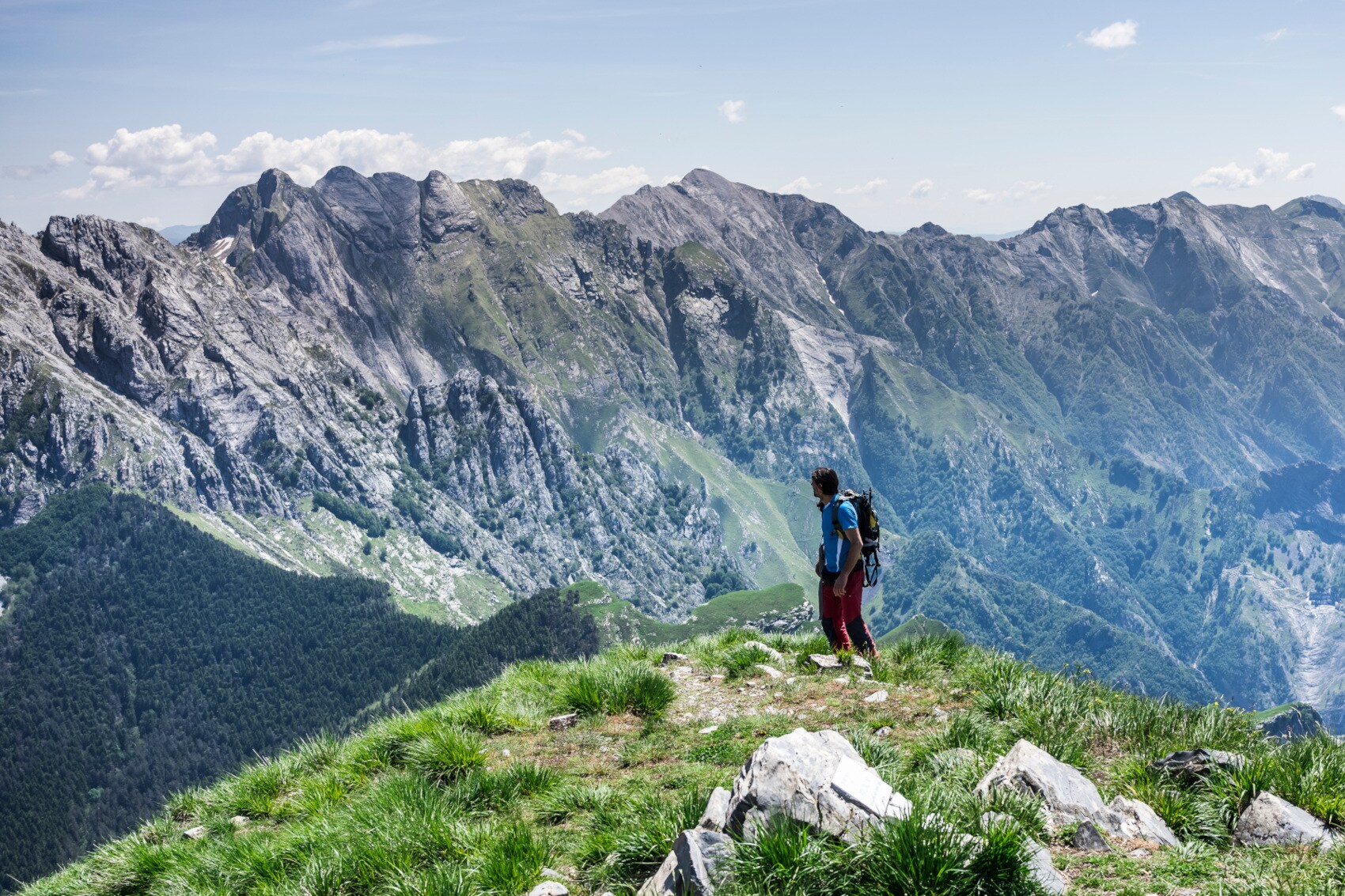 Eine Person steht auf einem Bergkamm, im Hintergrund ist eine Bergkette zu sehen Eine Person steht auf einem Bergkamm, im Hintergrund ist eine Bergkette zu sehen