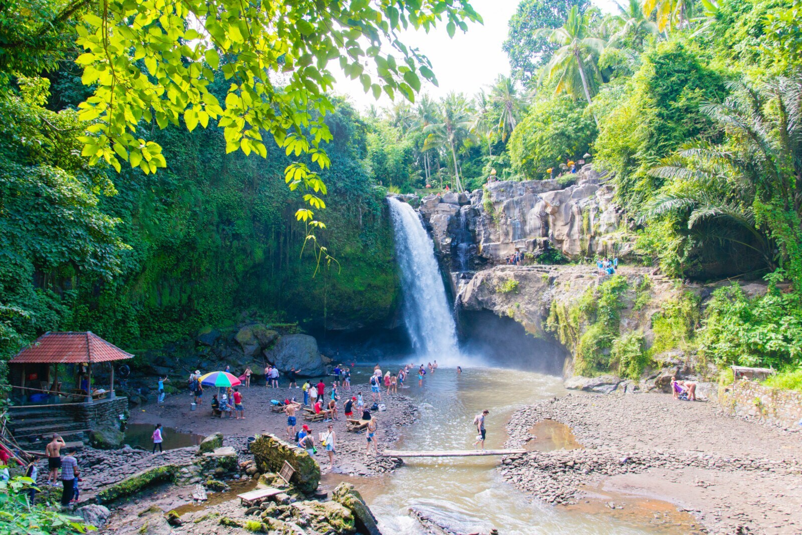 Menschen besuchen einen Wasserfall in einer grün bewachsenen Umgebung
