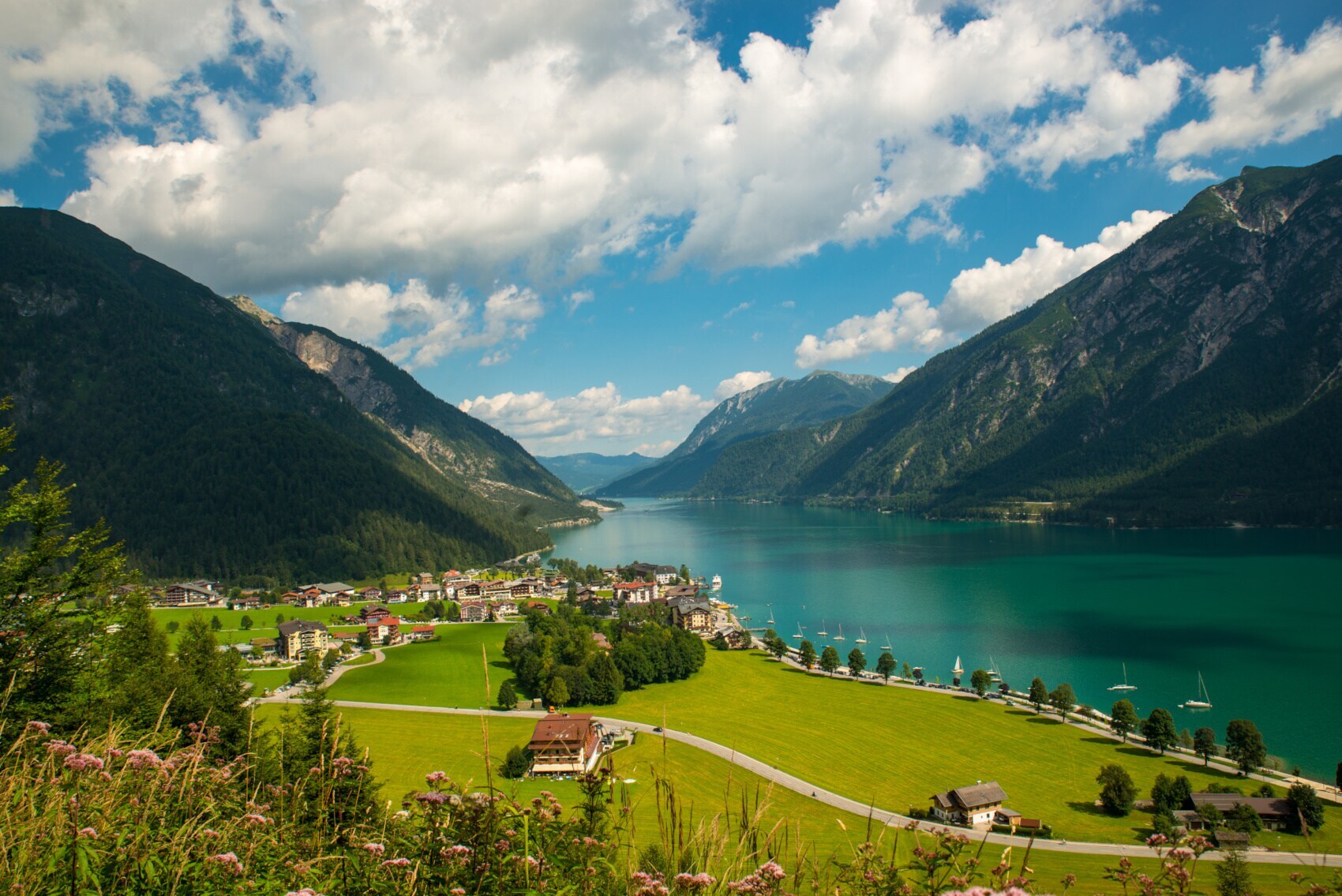 Ein türkisfarbener See zwischen Bergen und einem kleinen Dorf