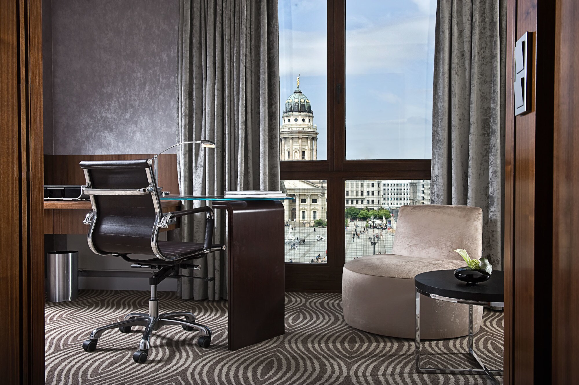 Luxuriöses Hotelzimmer mit Schreibtisch an einem bodentiefen Fenster mit Blick auf den Dom am Gendarmenmarkt in Berlin.