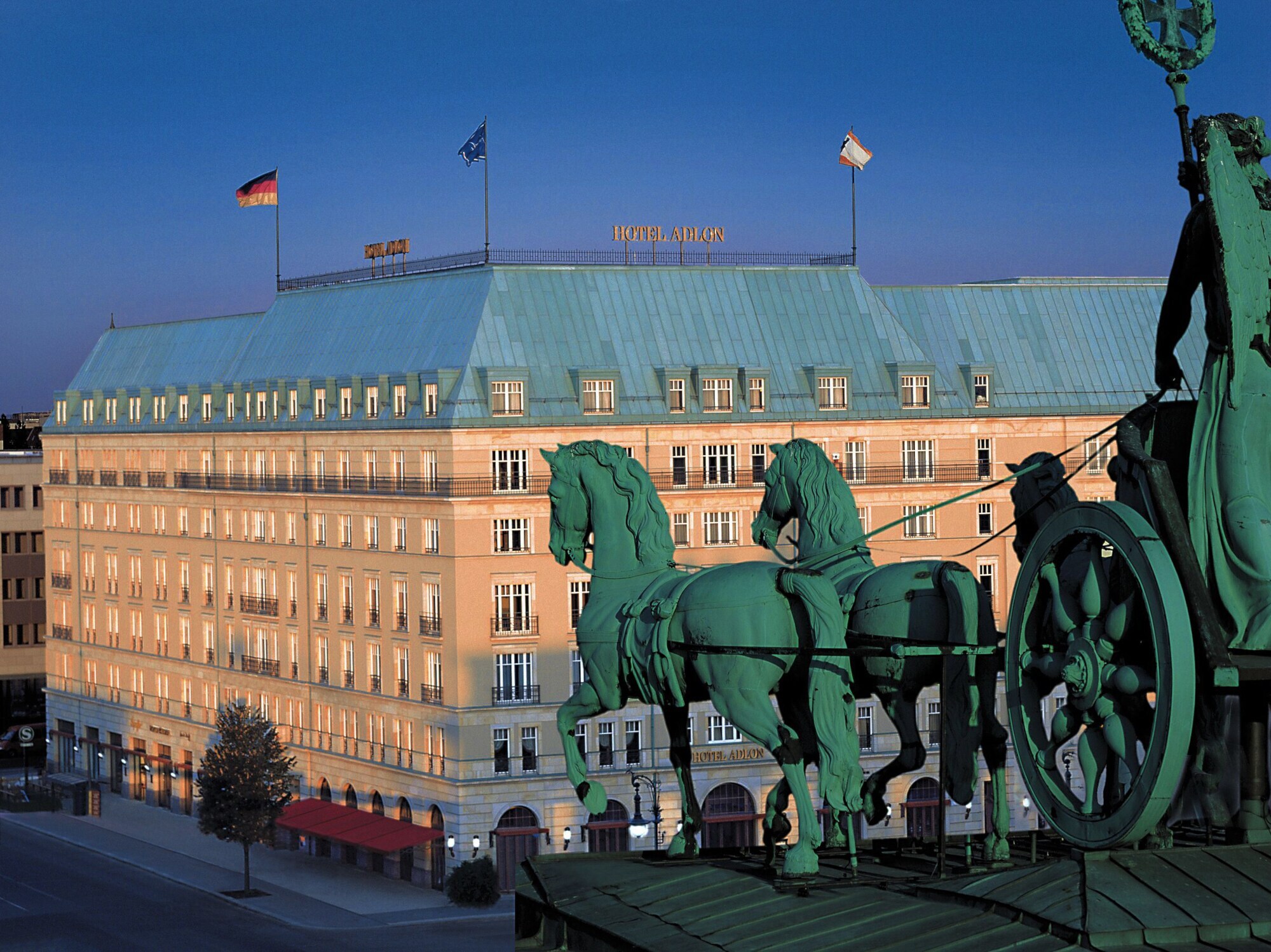 Luftaufnahme der Außenfassade des Hotel Adlon am Pariser Platz mit der Quadriga am Brandenburger Tor im Vordergrund.