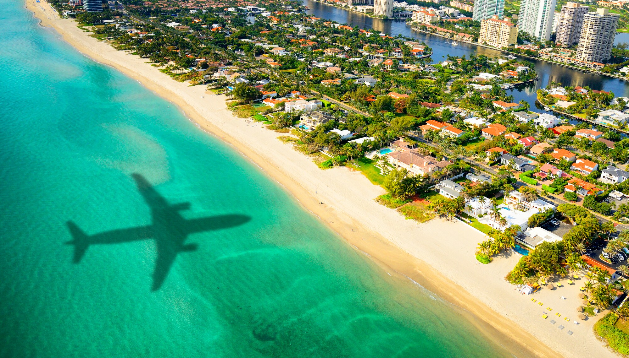 Luftaufnahme von Miami Beach mit dem Schatten eines Flugzeuges im türkisblauen Meer. Luftaufnahme von Miami Beach mit dem Schatten eines Flugzeuges im türkisblauen Meer.