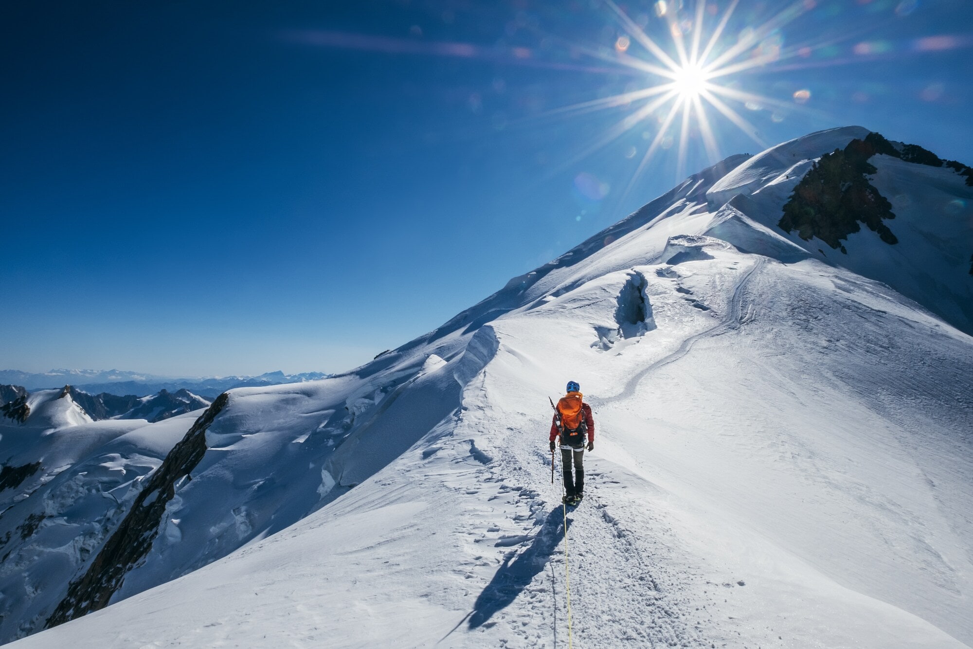 Before Mont Blanc (Monte Bianco) summitEine Person läuft einen verschneiten Bergkamm in Richtung des Gipfels hinauf Eine Person läuft einen verschneiten Bergkamm in Richtung des Gipfels hinauf