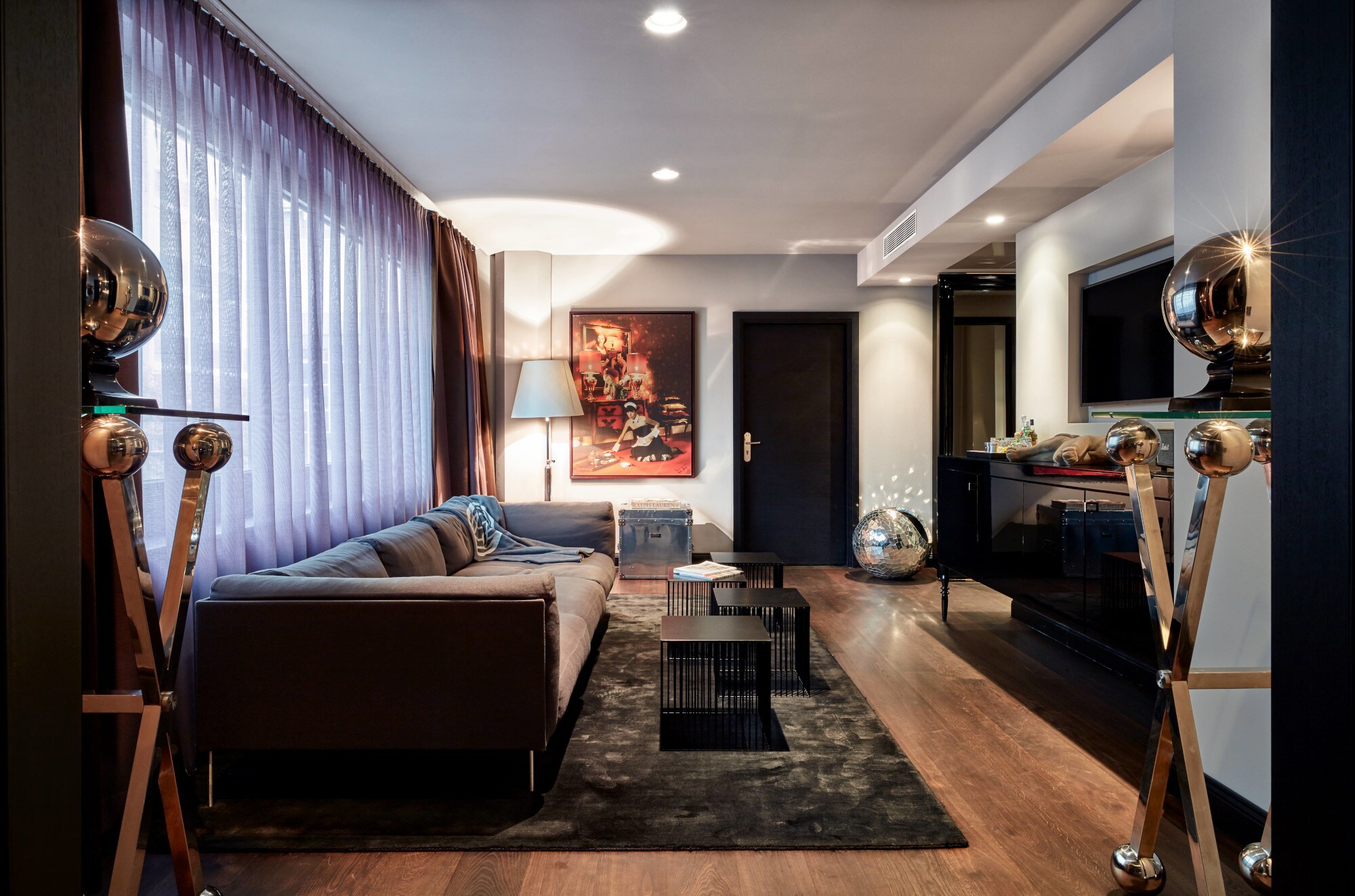 Moderne Hotelsuite mit Kunstwerken und silbernen Dekokugeln.