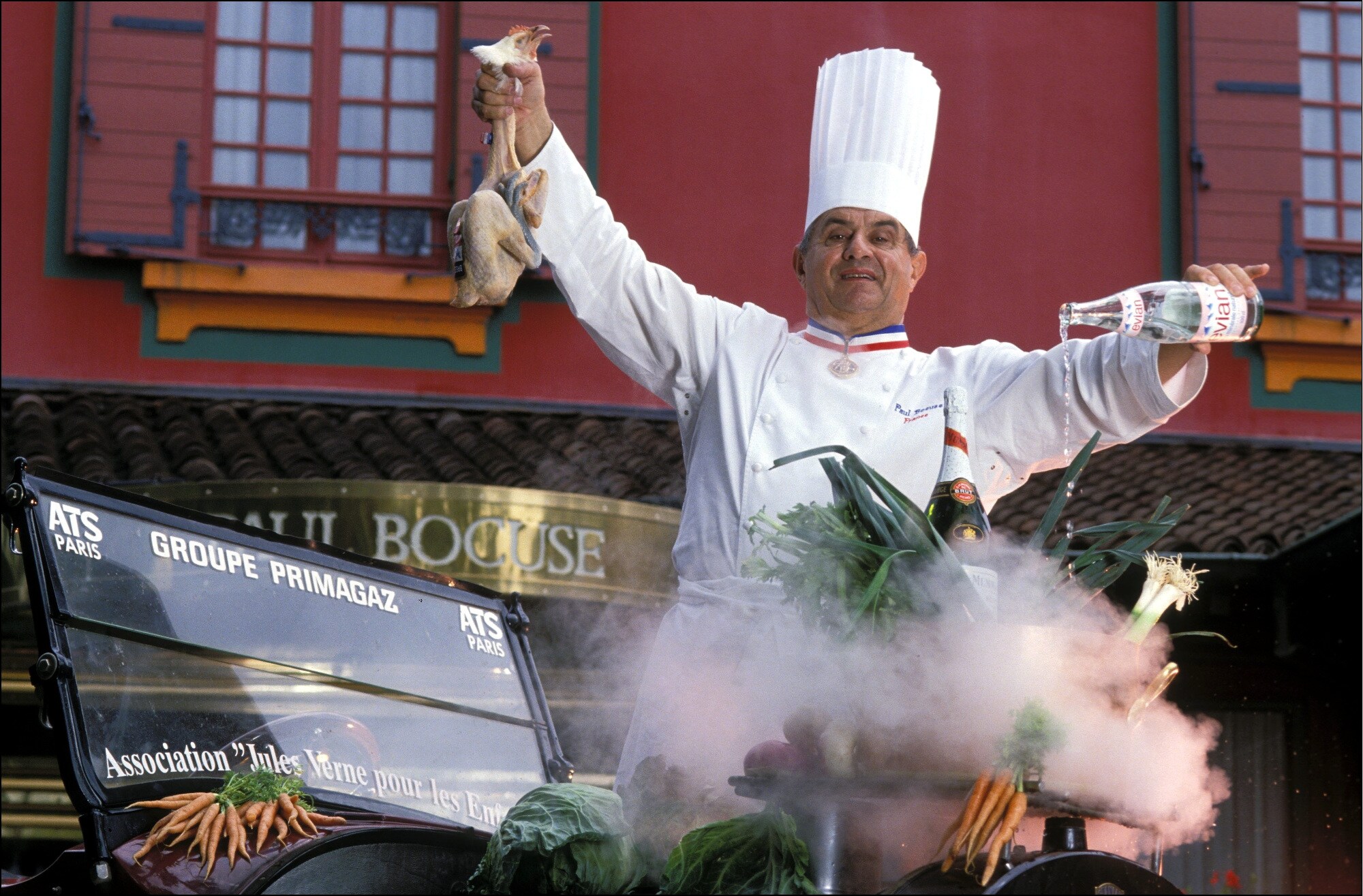 Paul Bocuse in Kochuniform bei einer Inszenierung mit Lebensmitteln vor seinem Restaurant Paul Bocuse in Kochuniform bei einer Inszenierung mit Lebensmitteln vor seinem Restaurant