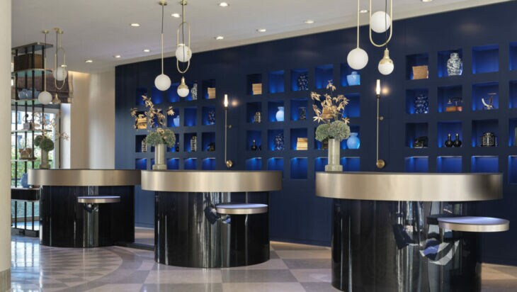 Moderne Hotellobby mit runden Empfangstresen und Designelementen vor blauer Wand.