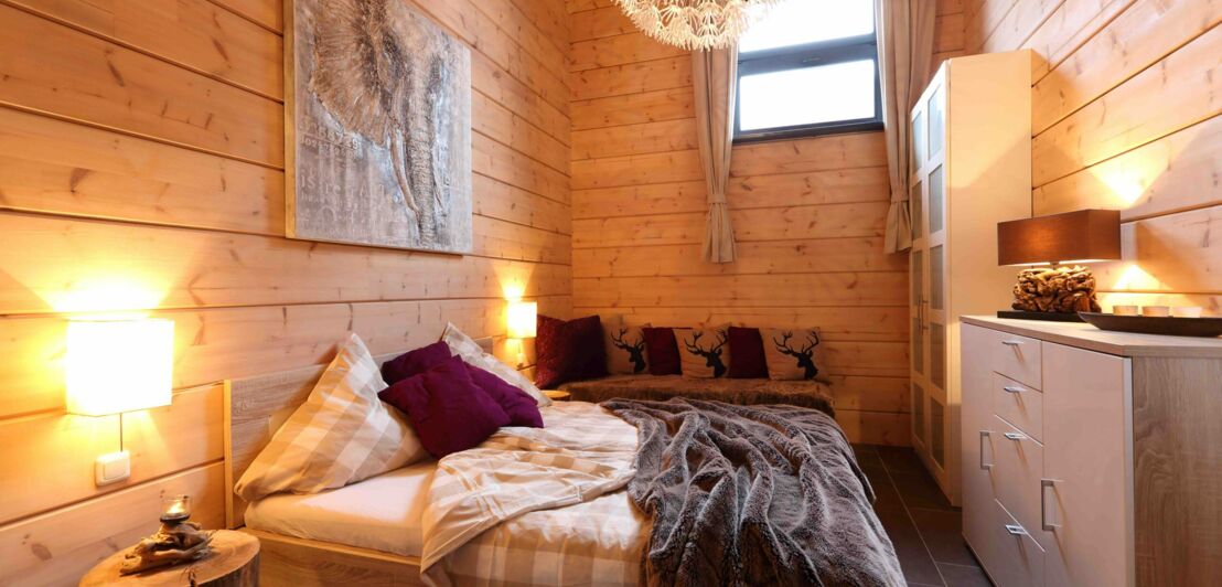 Ein gemütliches Bett in einem hellen Holzhaus