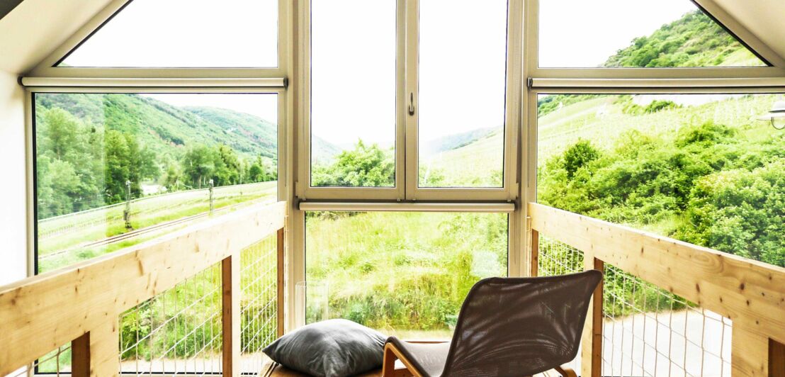 Ein Sessel vor einem Panoramafenster mit Blick auf die Weinberge