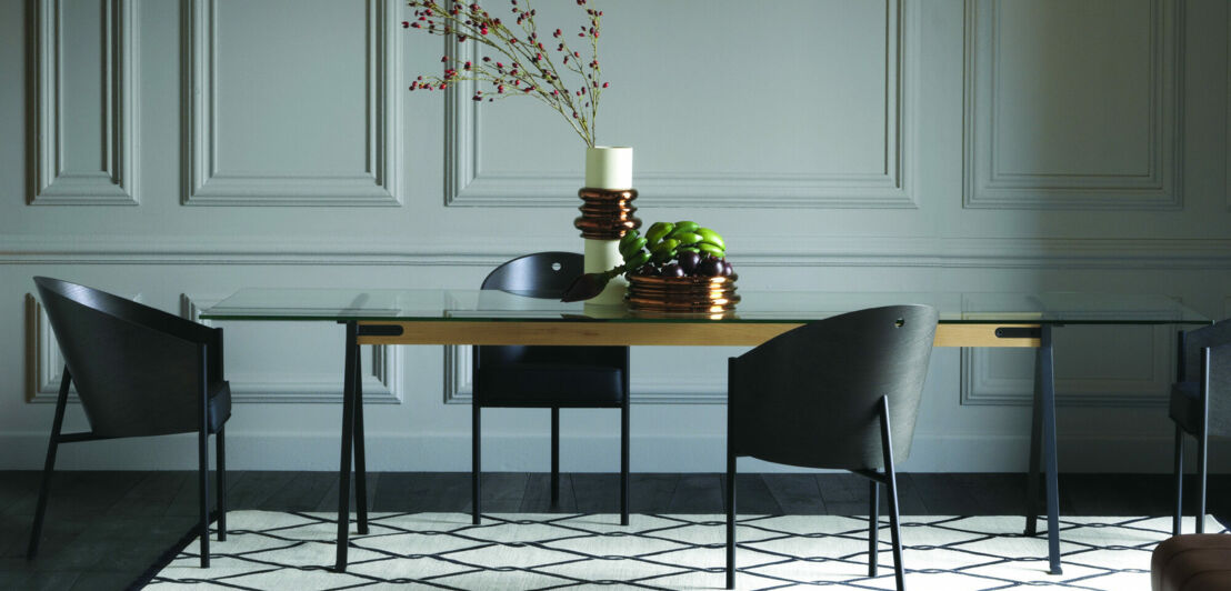 Drei graue Stühle stehen um einen Tisch mit Blumendekoration