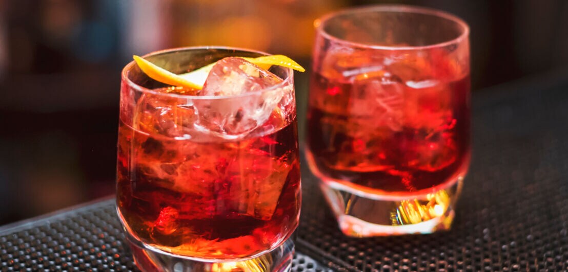 Zwei rote Cocktails mit Eis auf einem Tresen