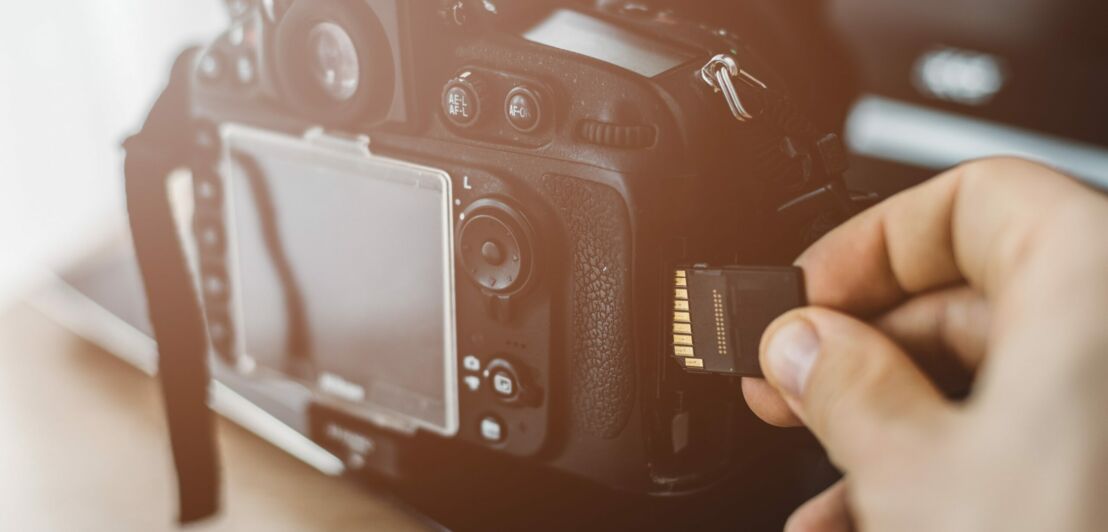 Eine Hand steckt eine Speicherkarte in einen Fotoapparat