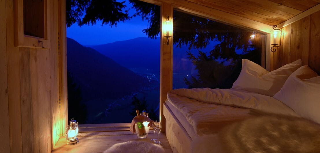 Ein Raum mit Wänden aus Holz mit einem Bett und Blick auf das Panorama