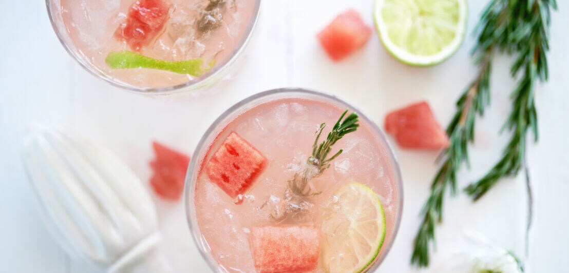 Getränk im Cocktailglas mit Eiswürfeln, Melone und Rosmarin