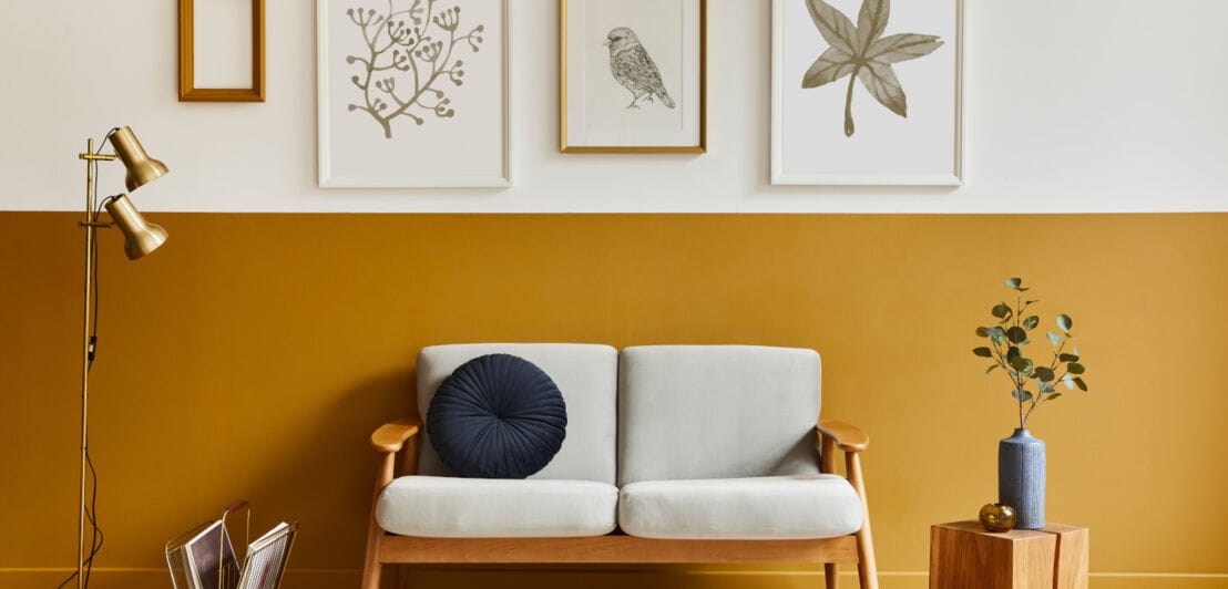 Ein Sofa vor einer gelb gestrichenen Wand mit Bildern