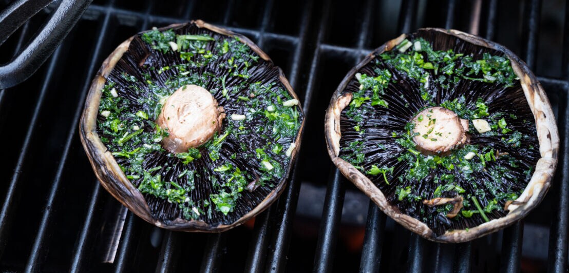 Zwei mit Kräutern marinierte Portobello-Pilze auf dem Grill