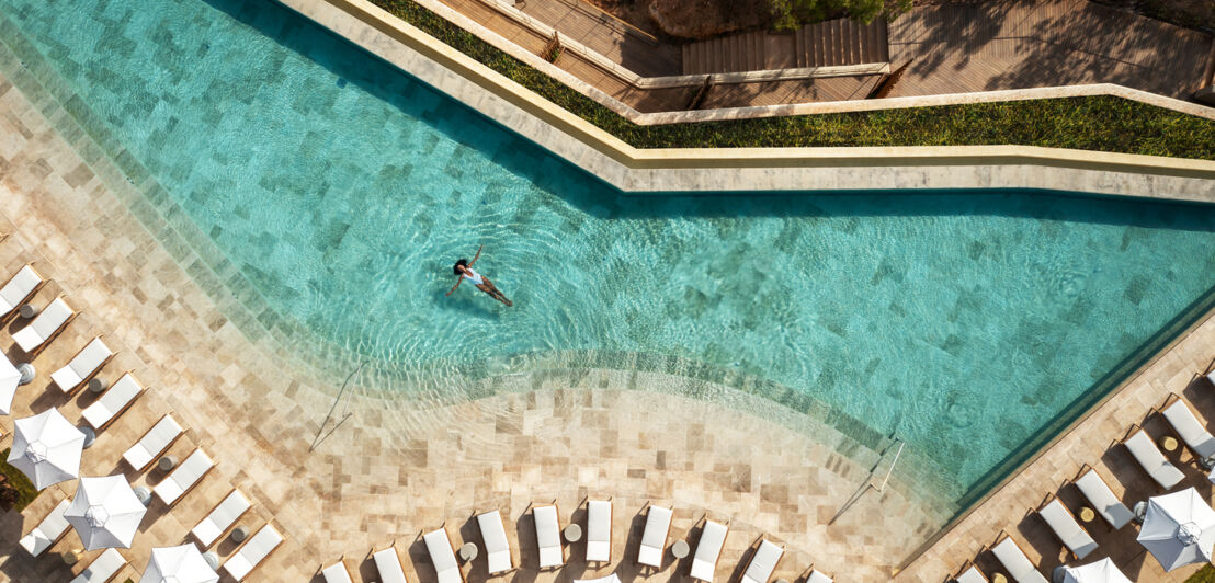 Eine Frau treibt auf dem Rücken in einem luxuriösen Pool