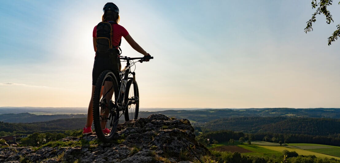 Ein Frau mit Mountainbike an einem Aussichtspunkt in der Fränkischen Schweiz