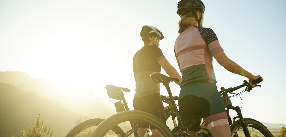 Ein Mann und eine Frau mit Mountainbikes genießen einen Ausblick