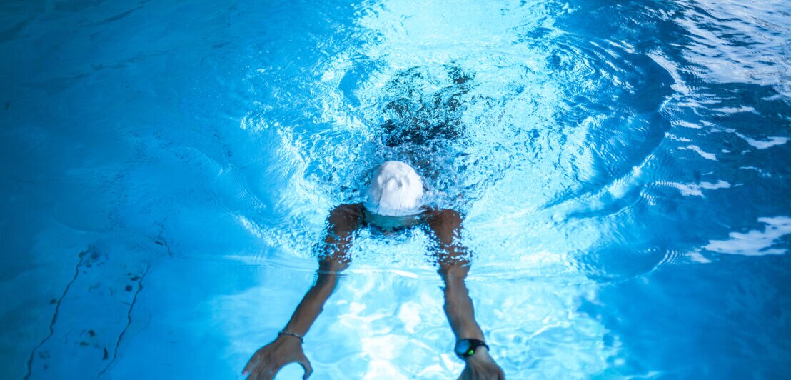 Eine Frau mit Schwimmkappe beim Schwimmen mit Smartwatch