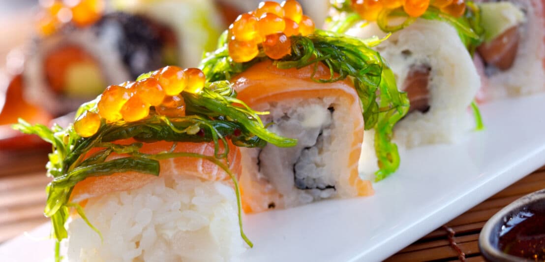 Sushi auf einer Platte mit Reis und orangenen Fischeiern