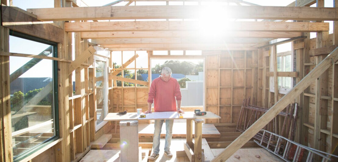 Ein Mann baut ein kleines Haus aus Holz