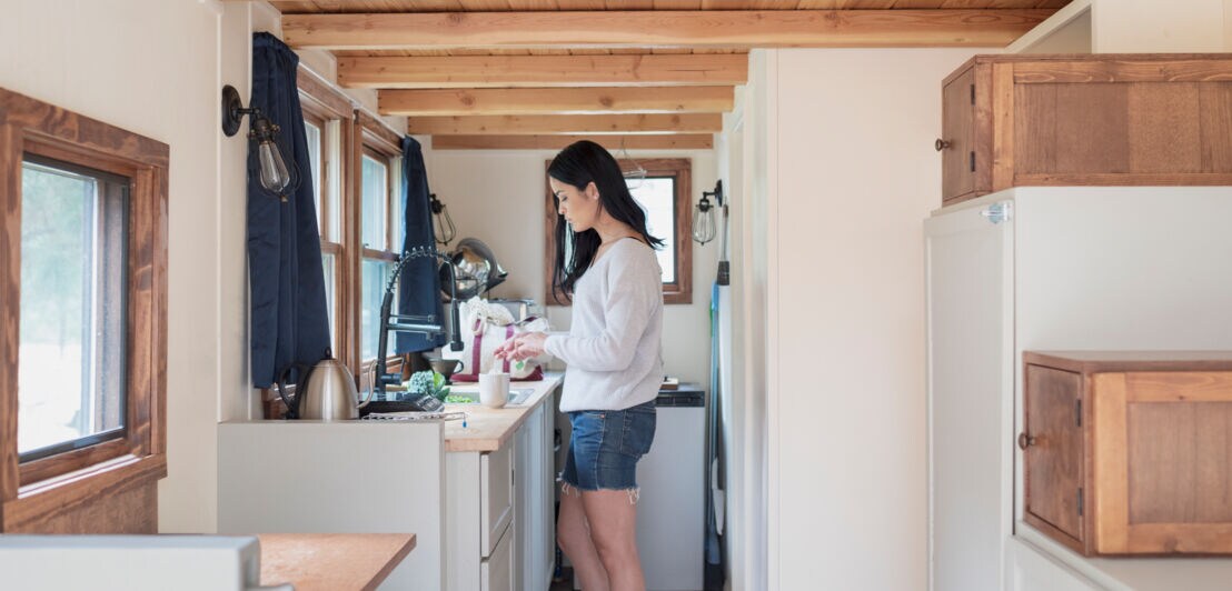 Eine Frau steht in einem Tiny House in der Küche