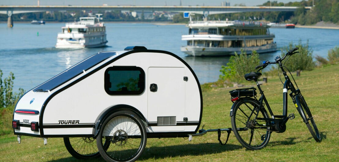 Ein Wohnwagen-Anhänger ist an einem Fahrrad befestigt