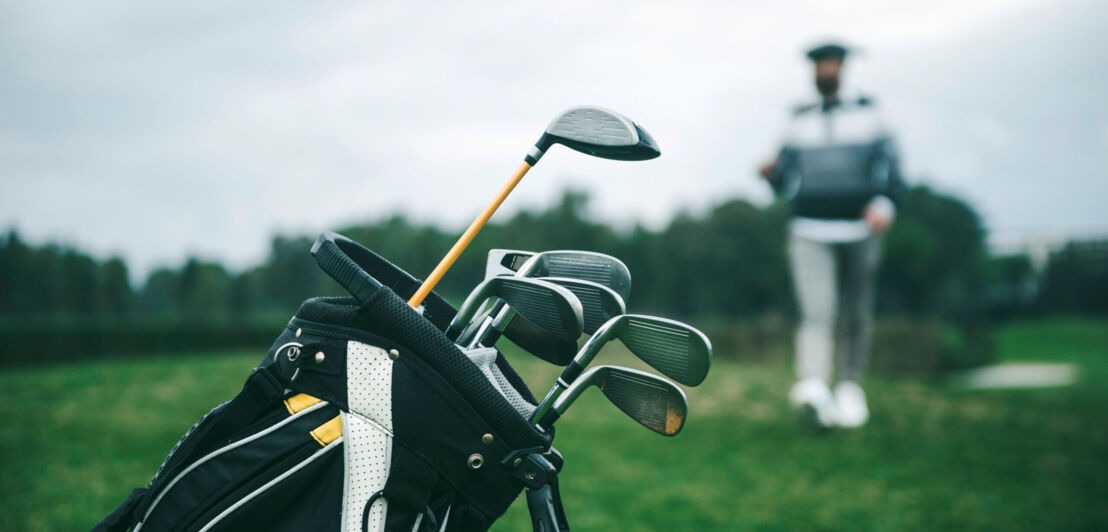 Ein Golfbag, aus dem mehrere Schläger ragen vor unscharfem Hintergrund