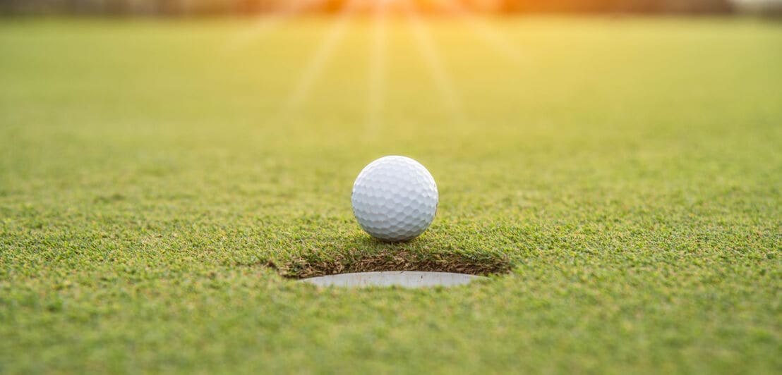 Golfball auf grünem Rasen am Loch