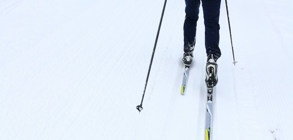 Eine Person auf Langlaufskiern im Schnee.