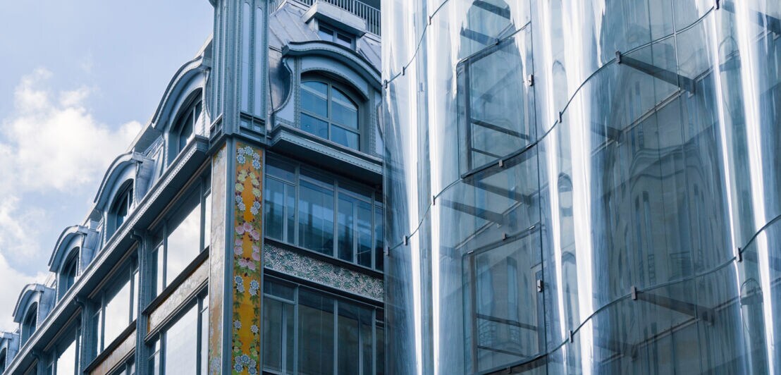 Eine alte, restaurierte Fassade trifft auf eine moderne Glasfront