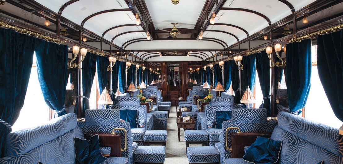 Innenraum eines luxuriösen Eisenbahnwagens mit blauen Samtsesseln und -vorhängen